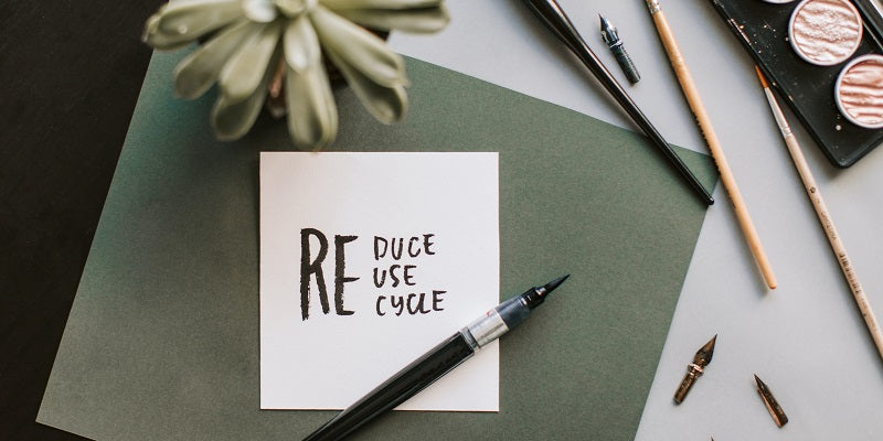 A piece of paper lying on a table reduce, reuse, recycle.jpg