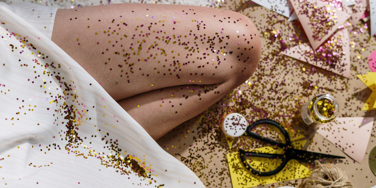 person kneeing on the ground with DIY supplies covered in glitter