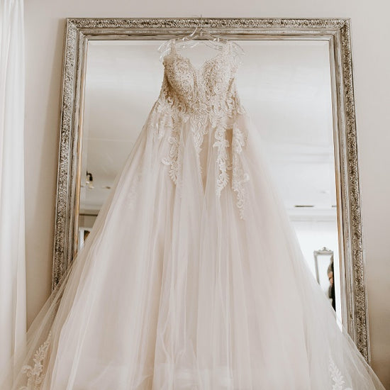 White wedding dress hanging in front of a mirror.jpg