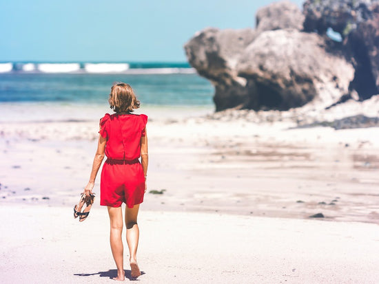 Woman in red clothes walking down a beach